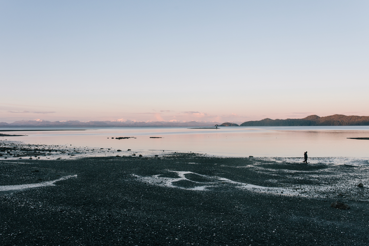 Sunset at Rathtrevor Beach. A person walks along the shoreline in the distance.