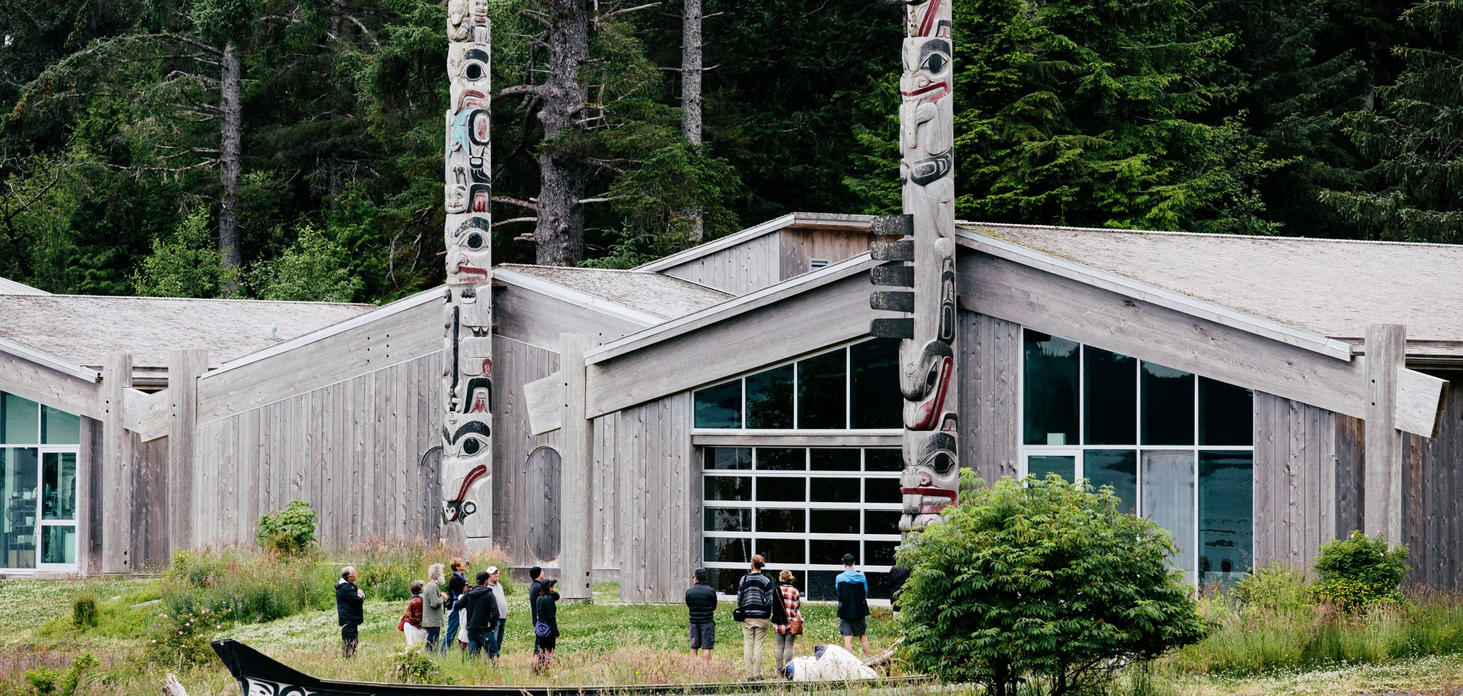 An outside view of the Haida Heritage Centre in Skidegate. Several people are gather around the front. 