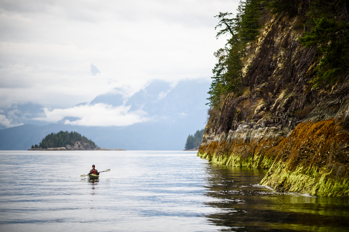 A kayaker paddles along the coastline of Desolation Sound at low tide.