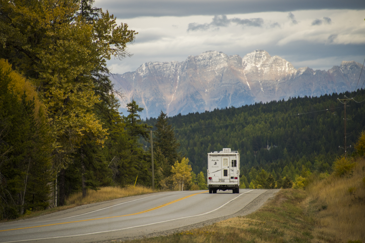 A camper van drives down the highway towards the mountains