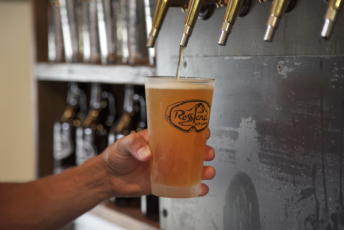 A person pours a glass of bear from a tap