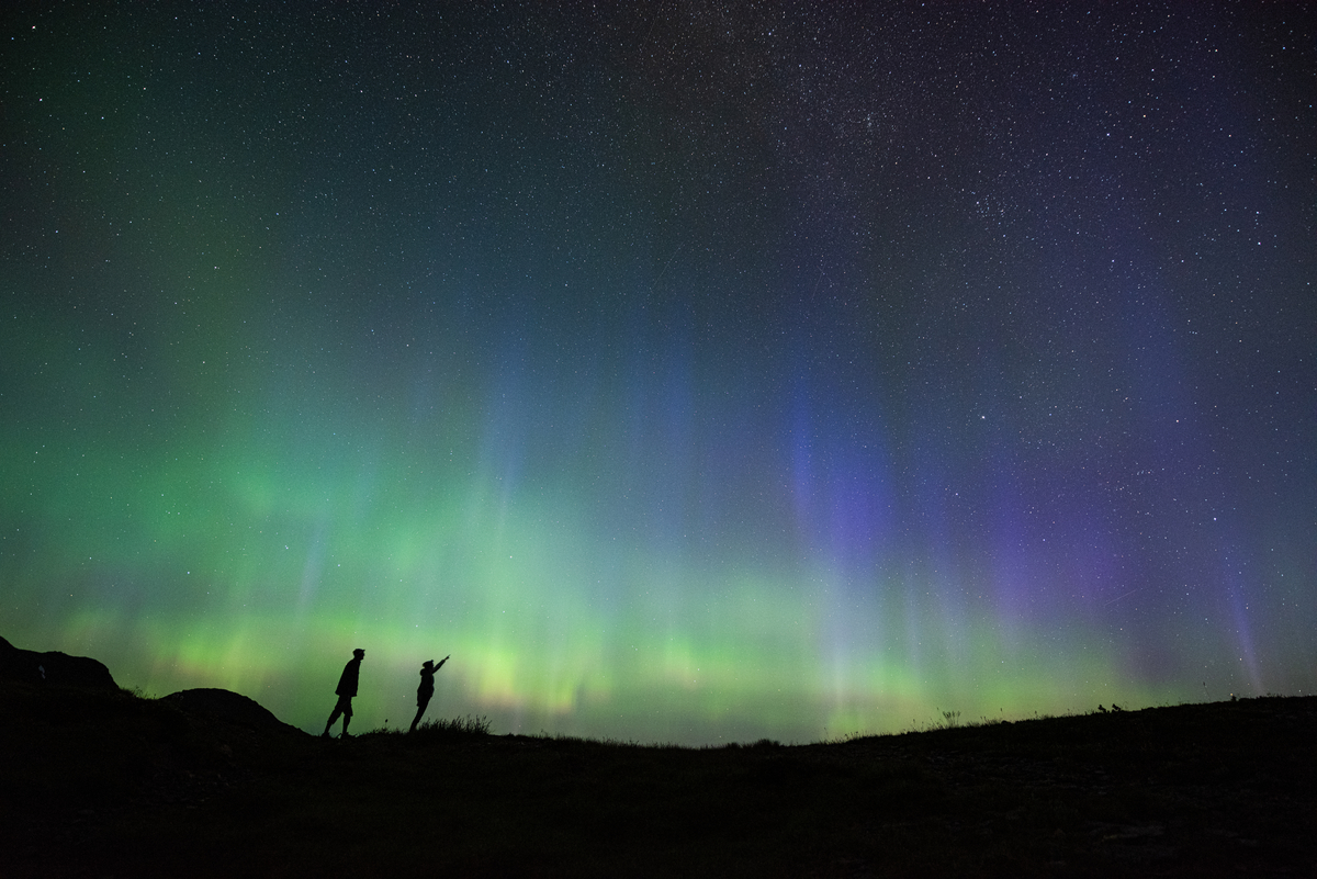 Two people look up at the Northern Lights in the Selkirk Mountains